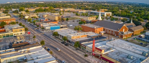 New apartments in Arlington highlighted by an aerial summer view of the surrounding DFW suburb landscape near Grand Prairie, Texas.