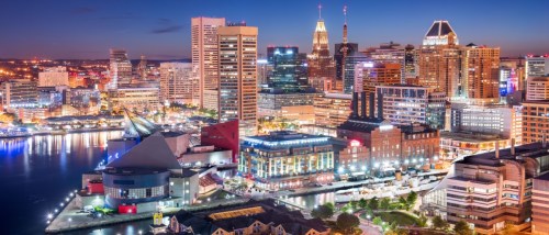 New apartments in Baltimore highlighted by the Inner Harbor skyline at dusk, featuring illuminated buildings and waterfront city views.