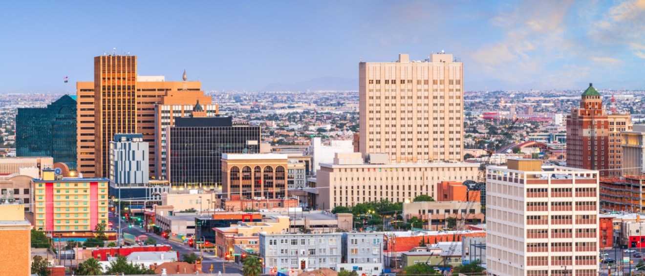 New apartments in El Paso highlighted by the downtown El Paso skyline at dusk, with views extending toward Juarez, Mexico, showcasing urban and cross-border cityscapes.