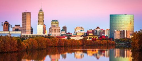 New apartments in Indianapolis highlighted by the city skyline along the White River at dusk, with modern buildings and soft evening light.