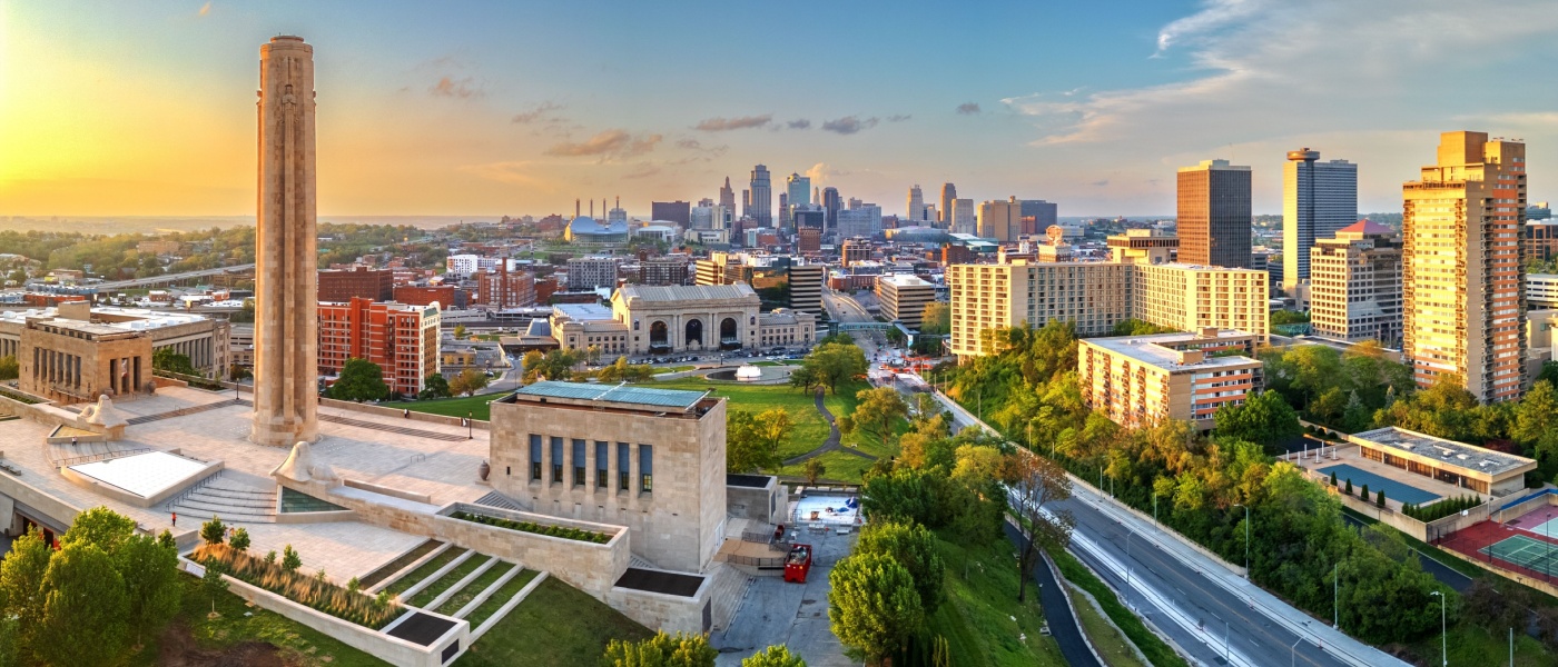 New apartments in Kansas City highlighted by the downtown skyline at dusk, with city lights illuminating the urban landscape.