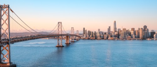 New apartments in Oakland highlighted by a sunrise view of the Oakland skyline and the Bay Bridge across the water.