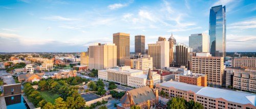 New apartments in Oklahoma City showcased by the downtown Oklahoma City skyline in the afternoon, featuring modern buildings and urban architecture.