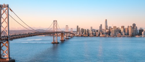 New apartments in San Francisco highlighted by a sunrise view of the skyline and the Bay Bridge spanning across the bay.