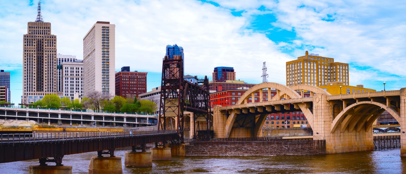 St. Paul, Minnesota skyline with skyscrapers and the Robert Street Bridge over the Mississippi River, highlighting city infrastructure and public transit connections in the urban area.