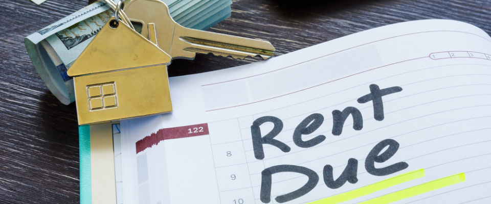 House-shaped keychain and apartment keys next to a calendar page marked “Rent Due,” representing rent collection schedules and monthly payment due dates.