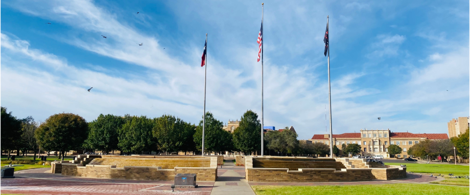Texas Tech University campus in Lubbock, Texas, showing open green space and flagpoles, highlighting the campus area that influences local apartment leasing and renter decisions.