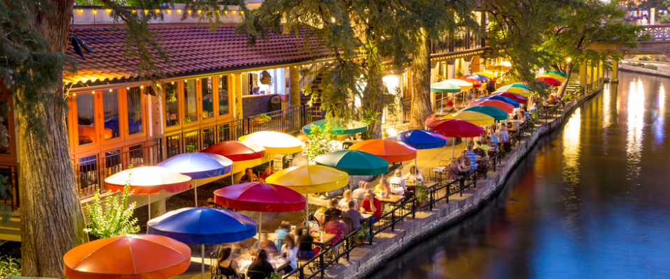 Colorful umbrellas lining restaurants along the San Antonio River Walk at dusk, showcasing the lively downtown setting renters should consider when asking key questions before choosing an apartment in San Antonio, TX.