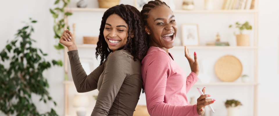 Friends singing and dancing together in their living room at home, showing the shared lifestyle of roommates who might apply for housing as co-applicants.