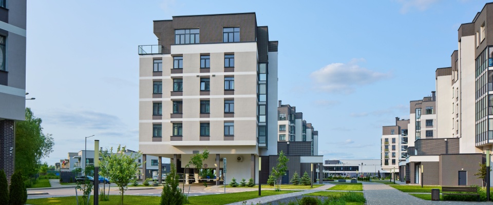 Modern apartment buildings in a green residential area, showcasing a new neighborhood with contemporary design and landscaped surroundings.