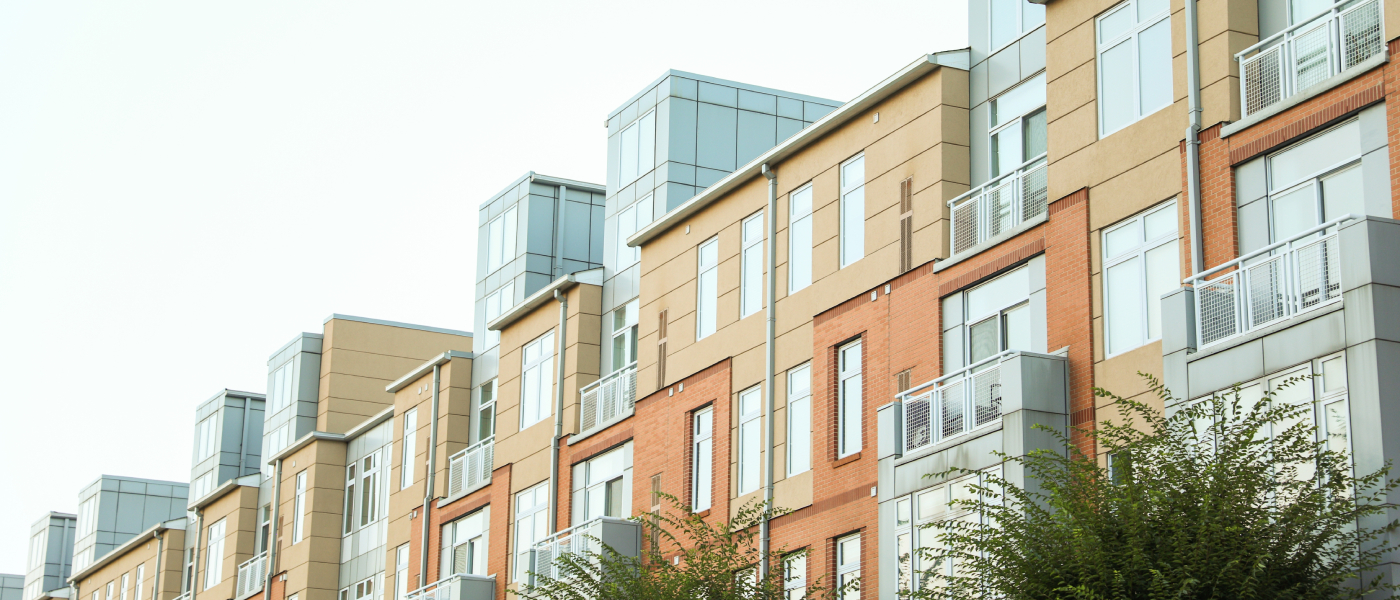 Row of modern apartment buildings with brick and neutral-toned facades, representing rental housing where renters may face a lease extension vs renewal decision.