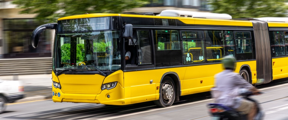 Modern yellow city bus in motion with motion blur, representing fast and efficient public transit in an urban area.
