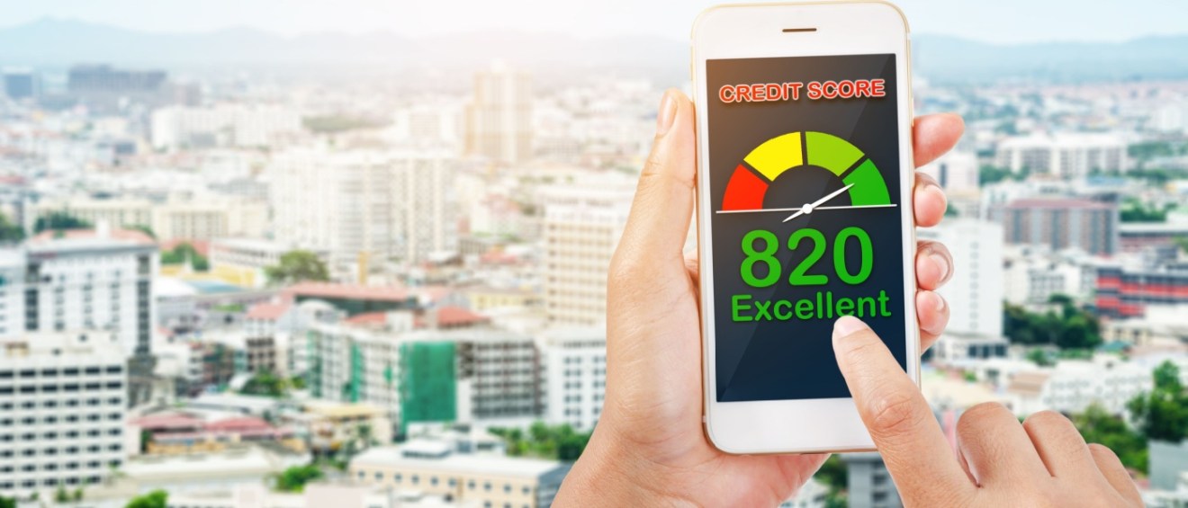 Close-up of a smartphone in someone's hands with a credit score for renting an apartment on the screen, and blurred cityscape with buildings in the background to illustrate the credit score for apartment approval.