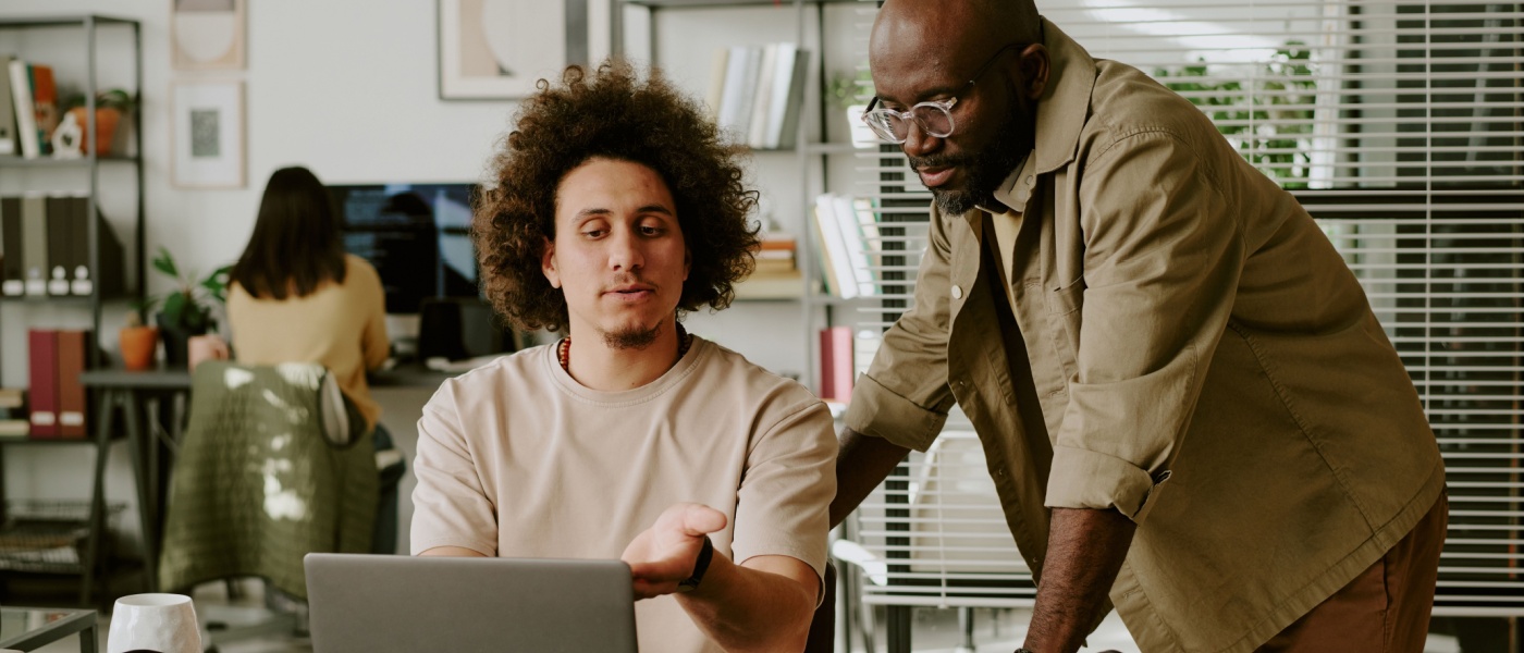 Team leader helping a coworker review documents and discuss details at a desk, illustrating communication and collaboration similar to a co-applicant reviewing an application together.