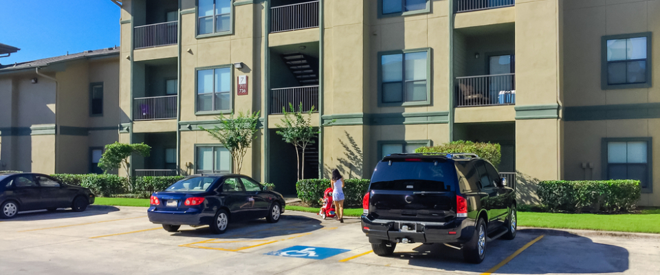 Apartment building with parking lot and covered balconies, highlighting key considerations like parking when renting in Albuquerque, NM.