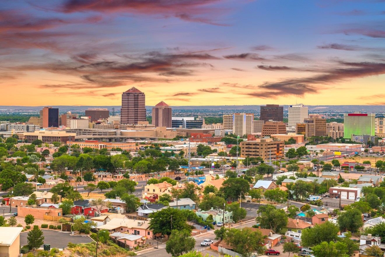 Colorful sunset over downtown skyline and residential neighborhoods, capturing the appeal of renting in Albuquerque, NM.