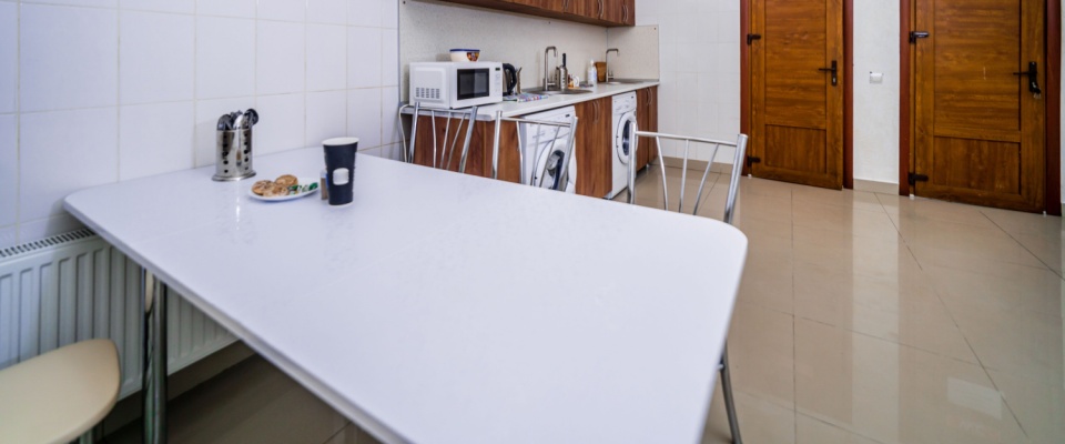 Shared dining and hallway area in a hostel with laundry drying space, illustrating common areas similar to club rooms for resident use.