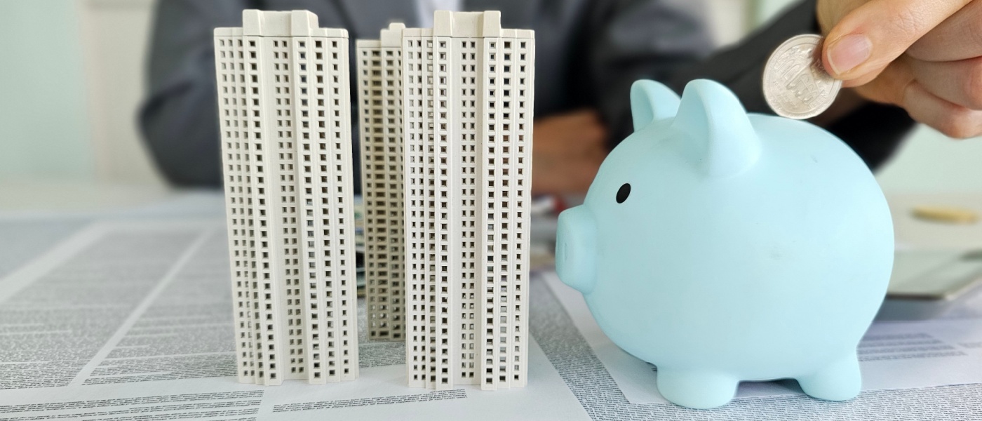 Businesswoman with a piggy bank and stacked coins beside a rising financial chart, representing savings and financial planning for a move-in budget.