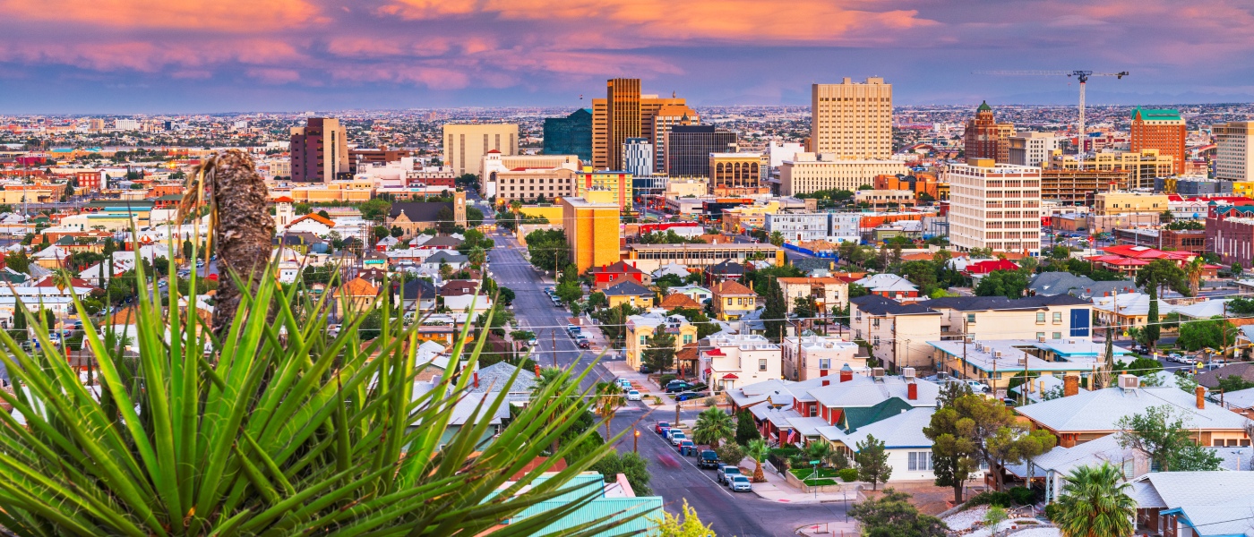 Apartments in El Paso highlighted by the downtown skyline at dusk, with views extending toward Juarez, Mexico in the distance.