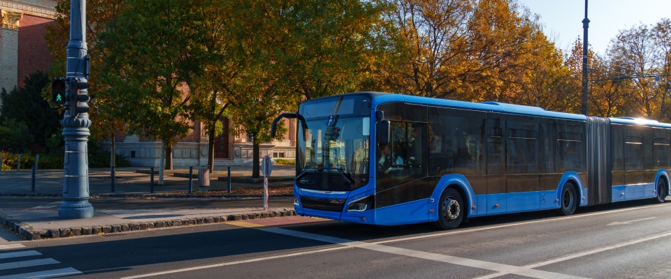 Blue city bus stopped at a crosswalk on an urban street, representing accessible public transit in Hartford and everyday city commuting.