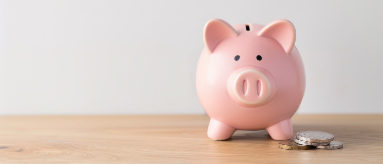 Pink piggy bank with coins on a wooden table representing savings from choosing an Obligo security deposit replacement option for renters.