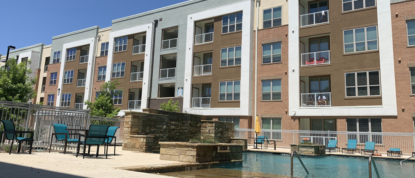 Modern apartment complex in Arlington, TX with a swimming pool, lounge seating, and balconies, showcasing amenities common in affordable neighborhoods for renters.