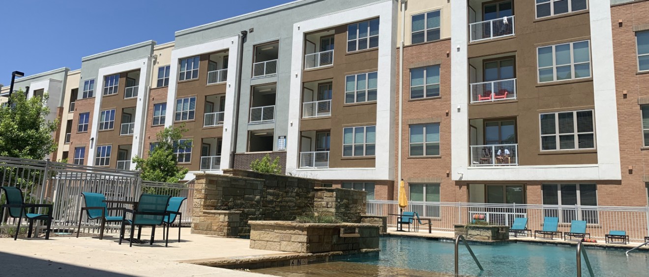 Modern apartment complex in Arlington, TX with a swimming pool, lounge seating, and balconies, showcasing amenities common in affordable neighborhoods for renters.