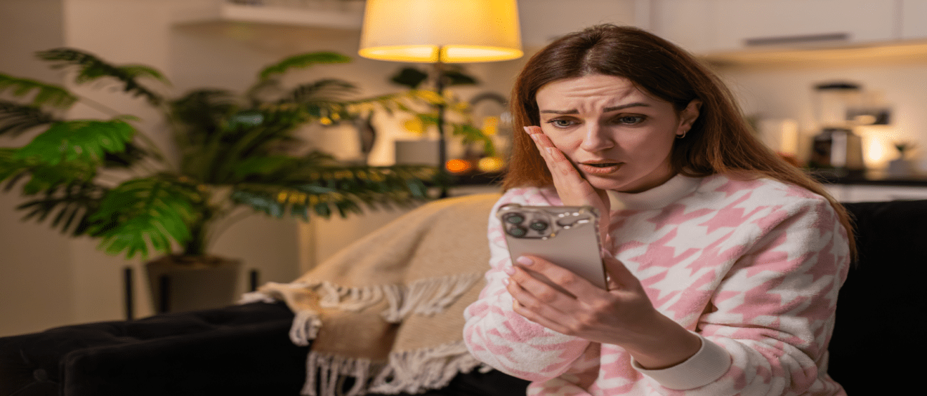 Disappointed woman sitting on a couch at night while looking at her smartphone, reacting to bad news similar to a rental application rejected notification.