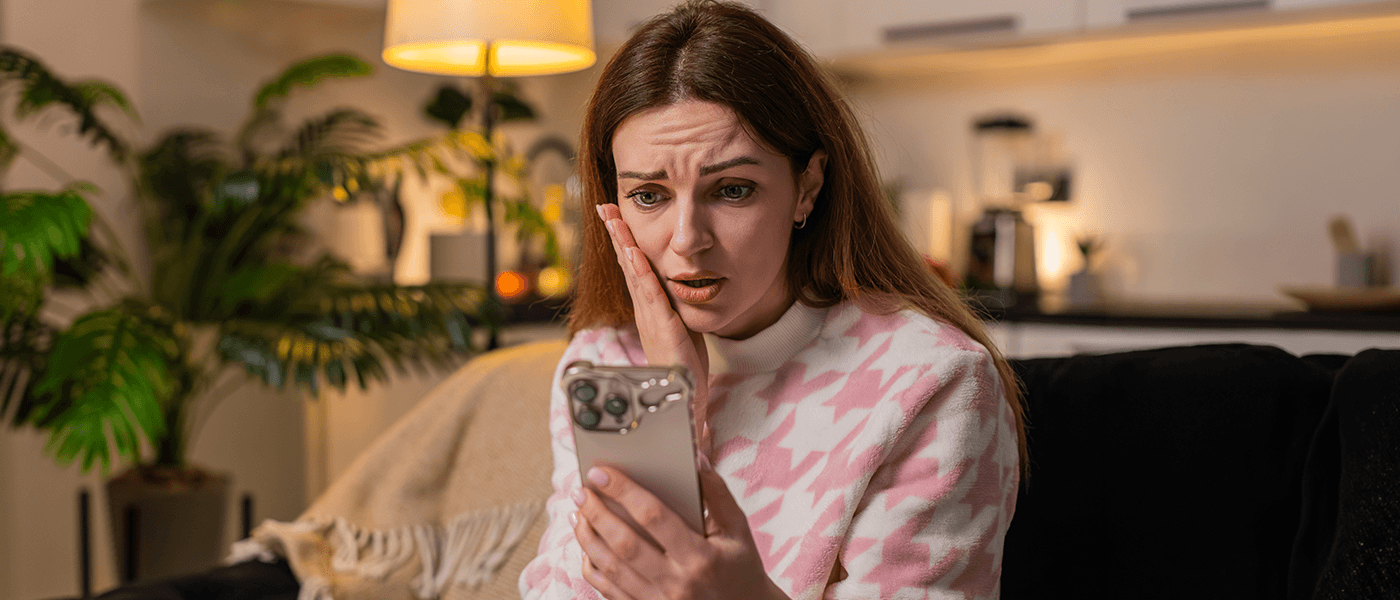 Disappointed woman sitting on a couch at night while looking at her smartphone, reacting to bad news similar to a rental application rejected notification.