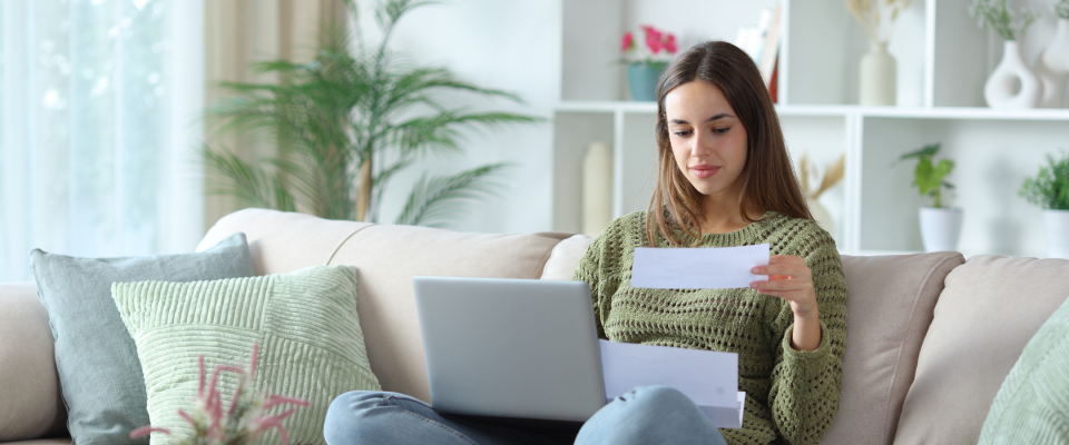 A person uses their laptop while checking their rental history report.