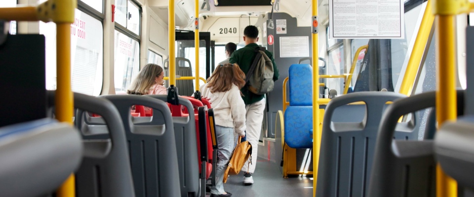 Passengers exiting a city bus at a transit stop and walking toward their destination, illustrating everyday public transit use and convenient urban mobility.