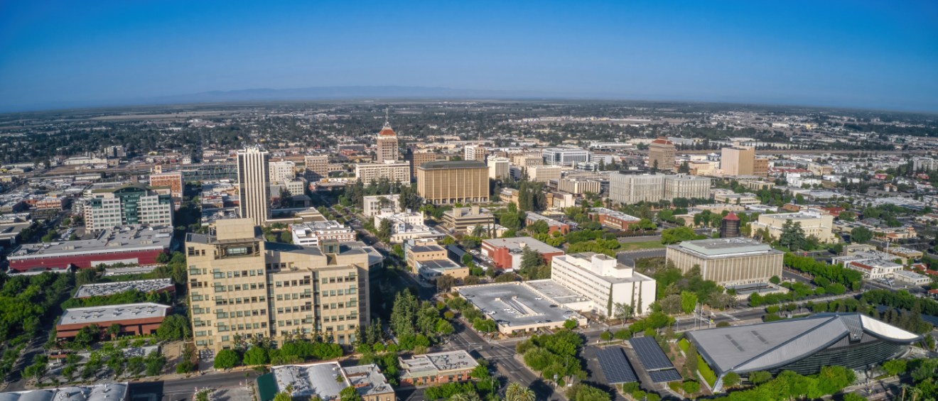 Sunny aerial shot of Fresno, CA's downtown core and the affordable neighborhoods filling the Central Valley around it.