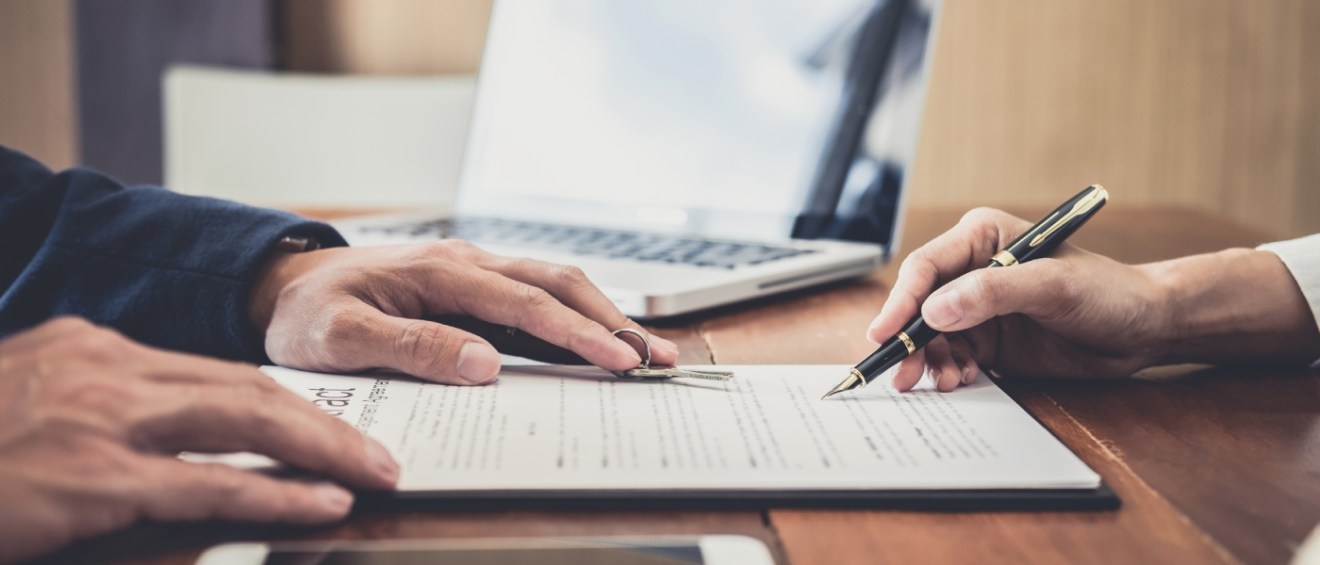 Property manager handing keys to a resident after signing a lease agreement, representing lease renewal season and ongoing rental housing decisions.