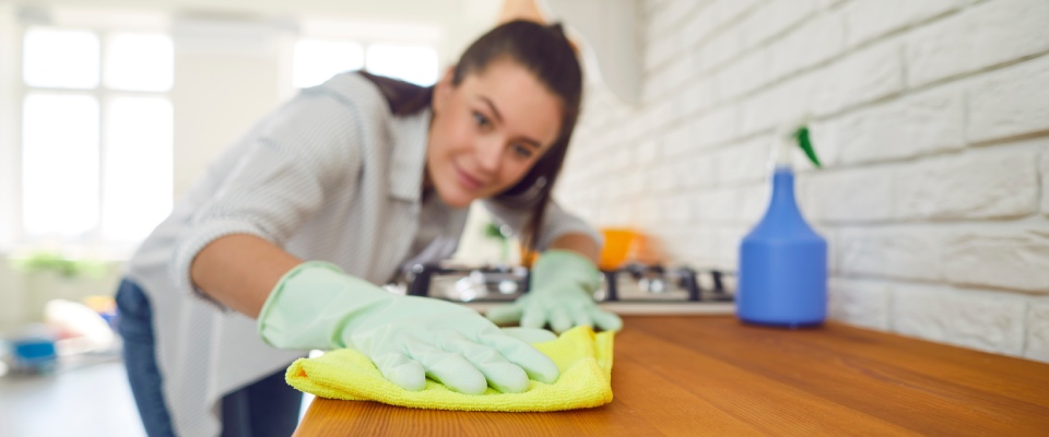 Woman cleaning and polishing a kitchen surface, highlighting cleanliness, property upkeep, and comfortable living in apartments in Tuscaloosa.