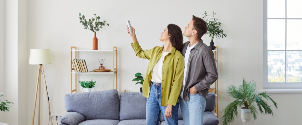 Family adjusting a wall-mounted air conditioner at home, highlighting climate control, comfort, and modern amenities available in apartments in Tuscaloosa.