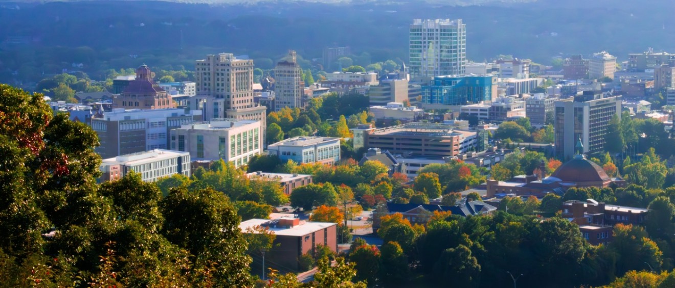 Apartments in Asheville highlighted by the city skyline with the Blue Ridge Mountains in the background, showcasing the area's scenic setting and urban environment.