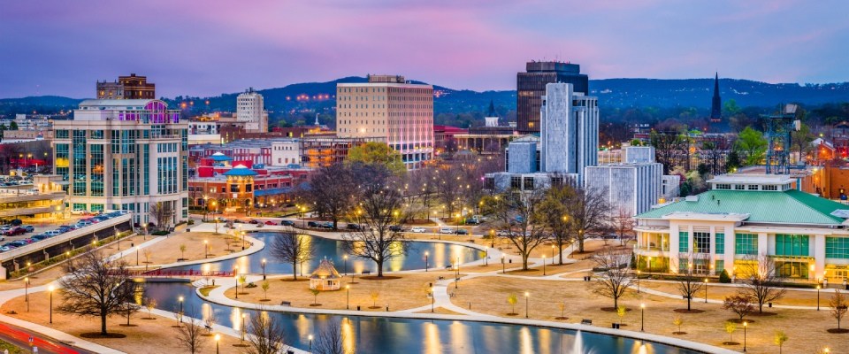 Best cities for renters highlighted by downtown Huntsville, Alabama, featuring a vibrant city skyline, green park spaces, and a thriving urban community at dusk.