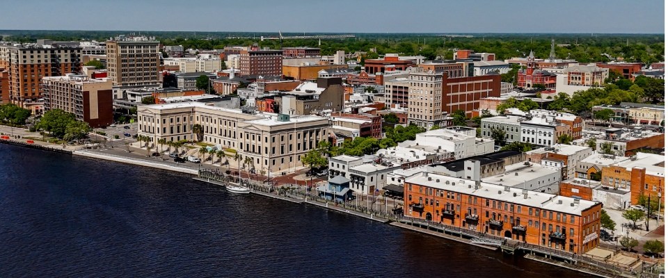 Best cities for renters highlighted by Wilmington, North Carolina's waterfront, featuring the Alton Lennon Federal Building, scenic riverfront views, and a vibrant downtown setting.