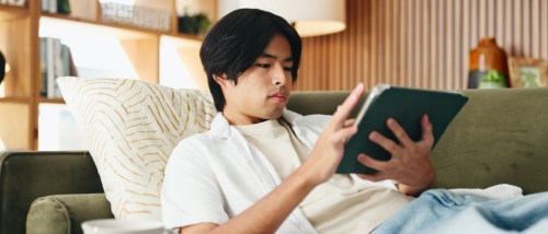 A college student using a tablet to browse for their first apartment.