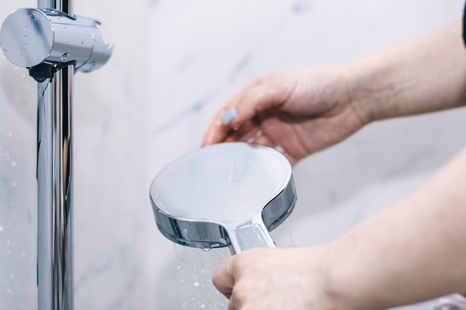person changing showerhead in rental apartment
