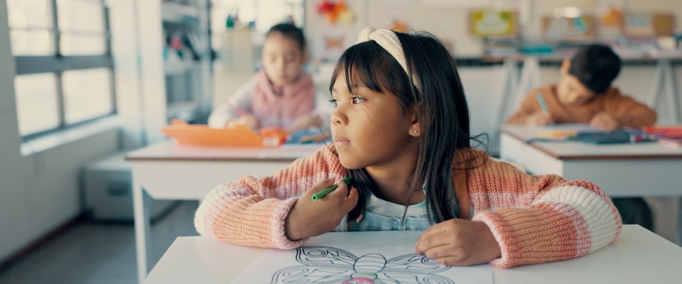 Young girl drawing a butterfly in a classroom, illustrating the learning, creativity, and family priorities of millennial renters with kids.