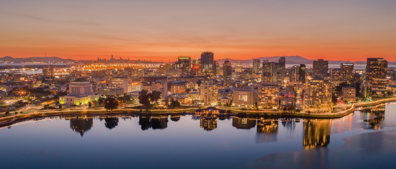 Aerial view of the Oakland skyline at sunset, highlighting the city's urban landscape and affordable neighborhoods for renters.