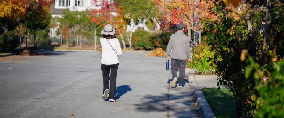 Couple walking along a street lined with autumn trees in one of the walkable cities in California, USA.