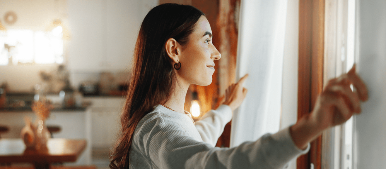 person looking out window in apartment