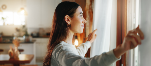 person looking out window in apartment