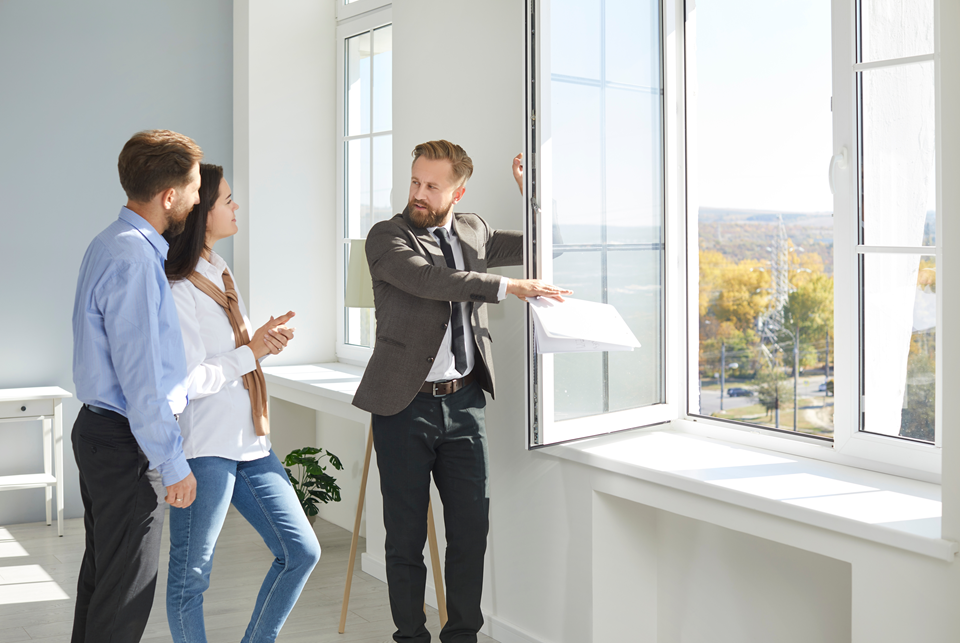 real estate agent showing a young couple how windows open in a rental apartment