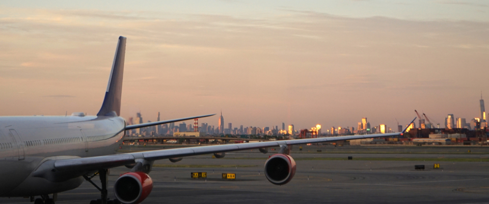 Airplane on the tarmac at Newark Liberty International Airport at sunset, with the Manhattan skyline beyond — a hub Newark public transit connects to.