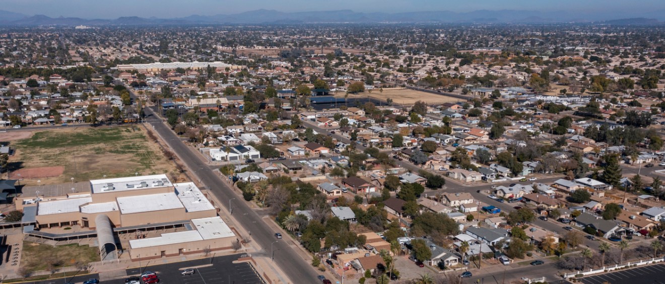Aerial view of one of the affordable neighborhoods in Glendale, AZ, with homes, a school, and mountains in the distance.