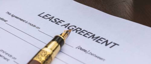 A residential lease contract form placed on a desk alongside a calculator and pencil, representing the paperwork involved in understanding how to break a lease.