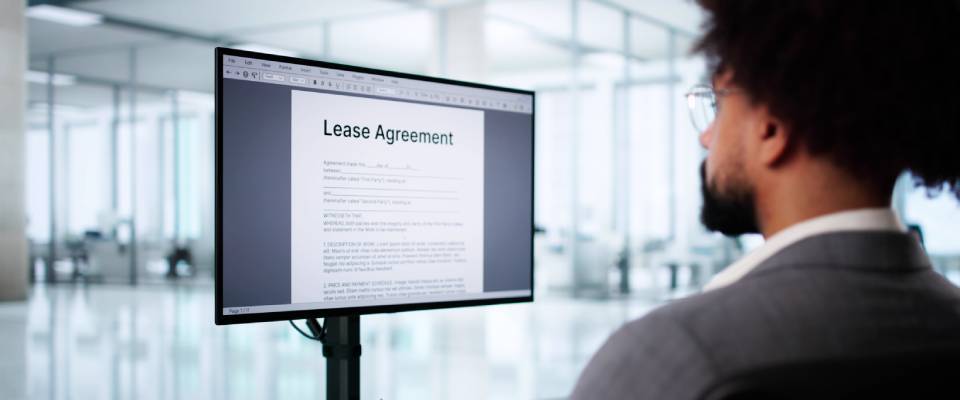 A man examines a lease agreement on a digital tablet, reviewing the terms and conditions related to how to break a lease.